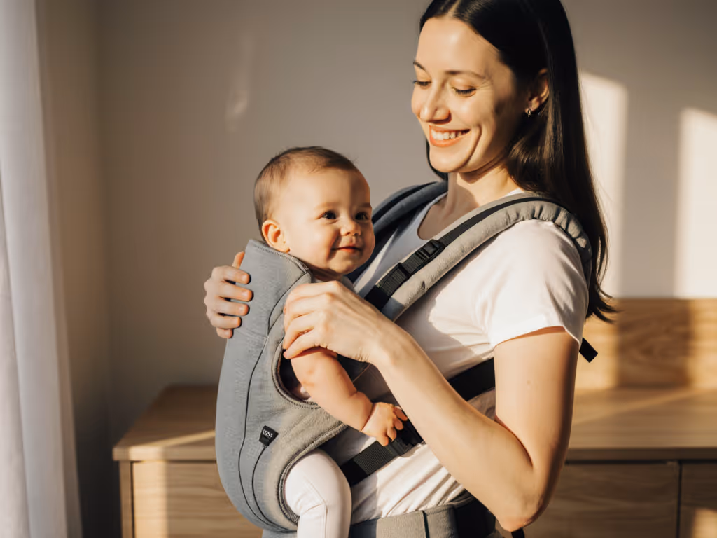 caregiver smiling while checking baby's position in carrier